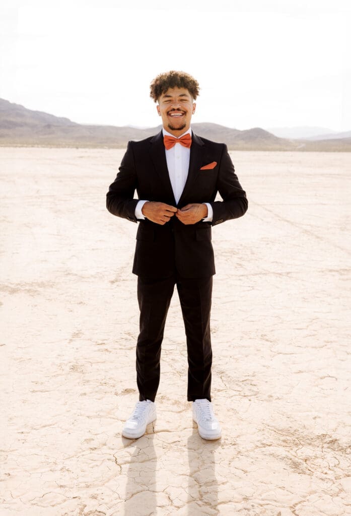 groom smiling buttoning up his suit