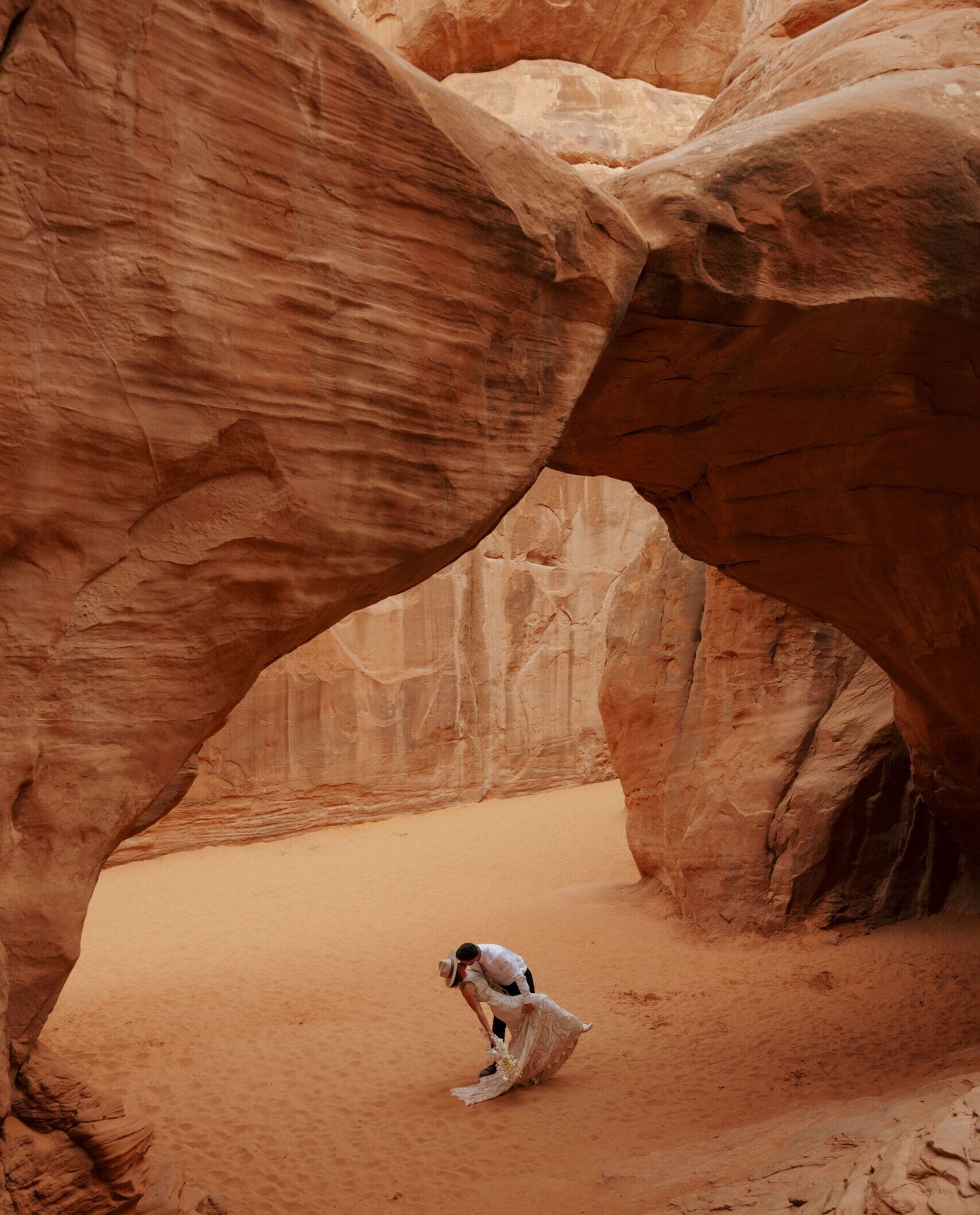 bride and groom kissing under natural arch in moab
