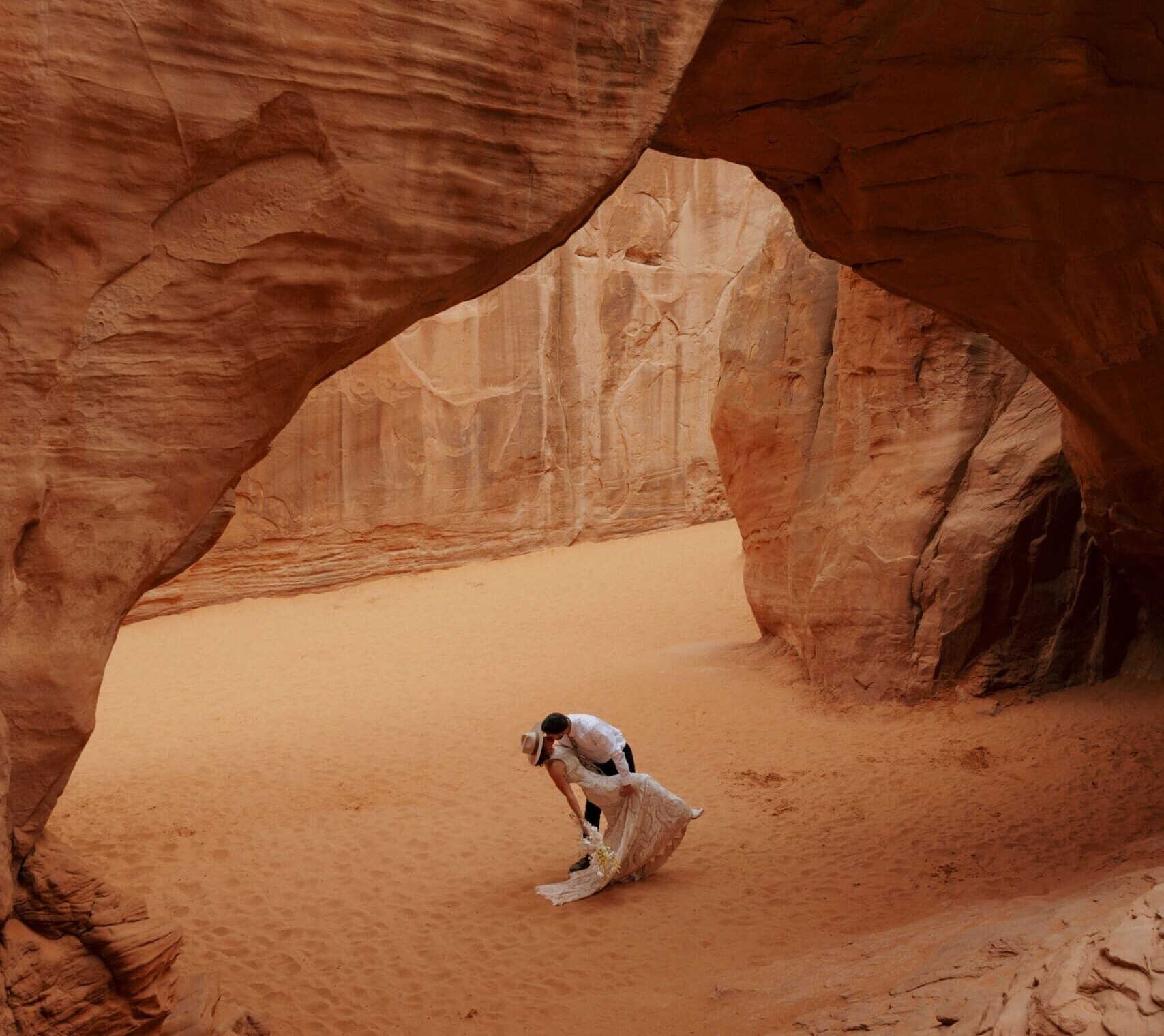 bride and groom kissing under natural arch in moab