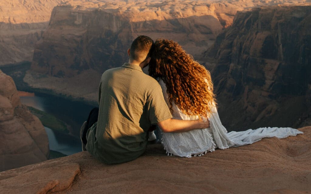 couple sitting on the edge of a cliff