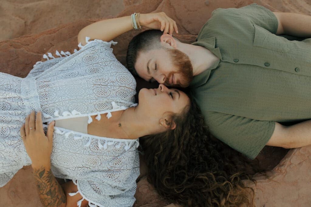 couple laying down on red rocks