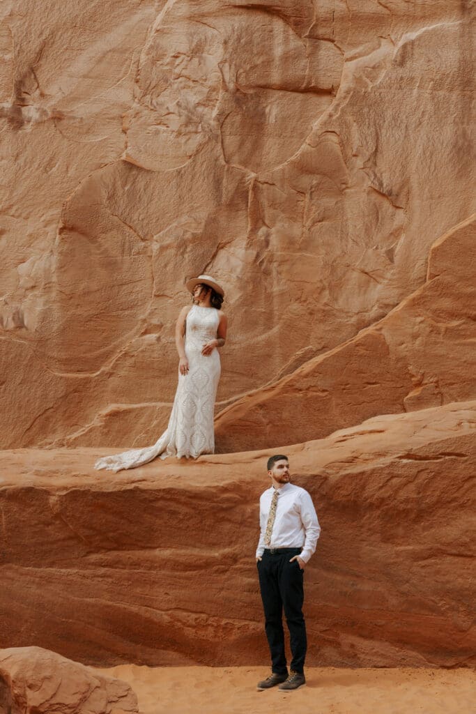 couple looking opposite directions standing on red rock