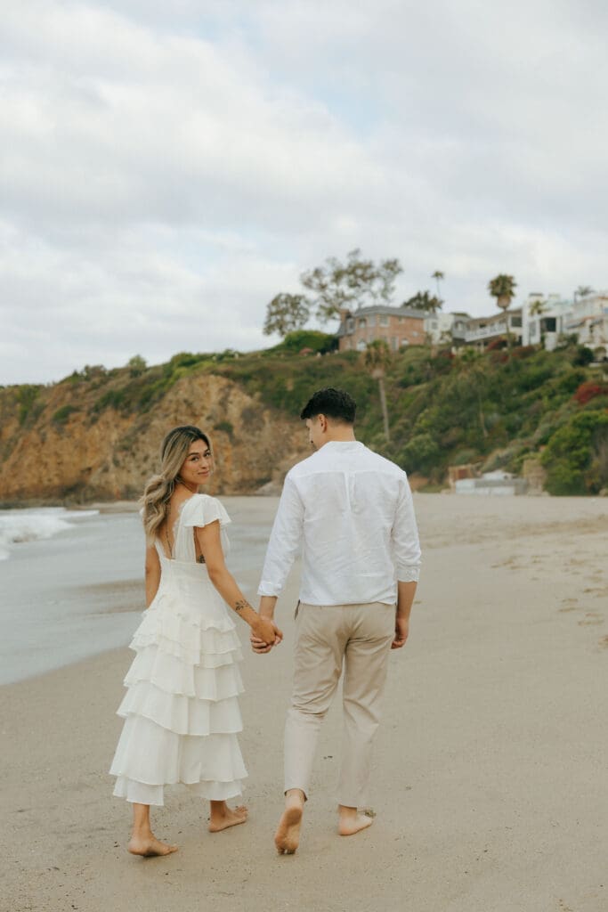 couple holding hands walking on the beach