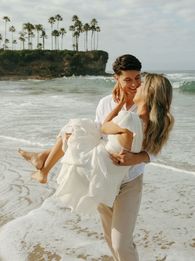 couple at laguna beach while the guy is carrying her