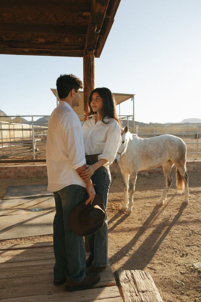 couple holding hands in a horse ranch
