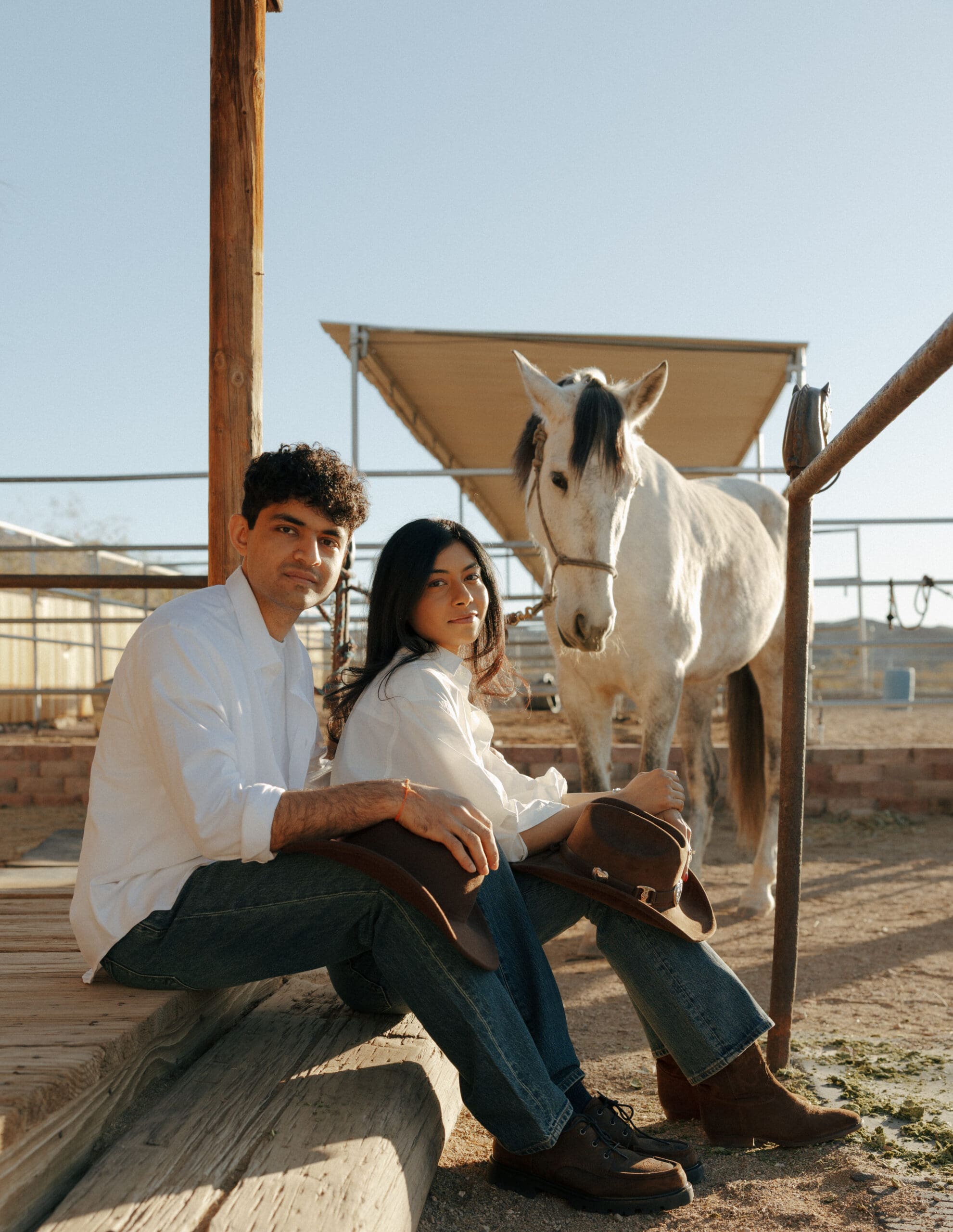 couple sitting down with a white horse