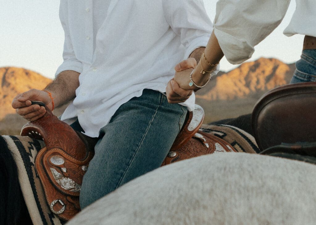 couple riding horses holding hands