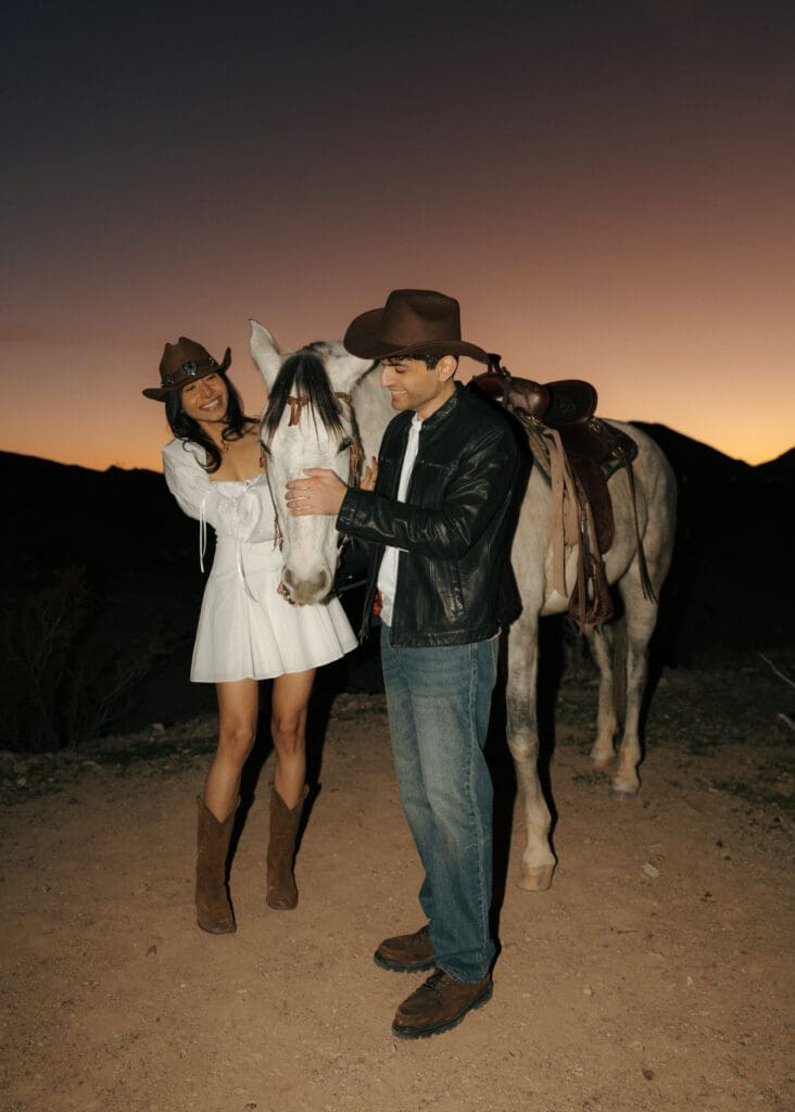couple petting a white horse during sunset