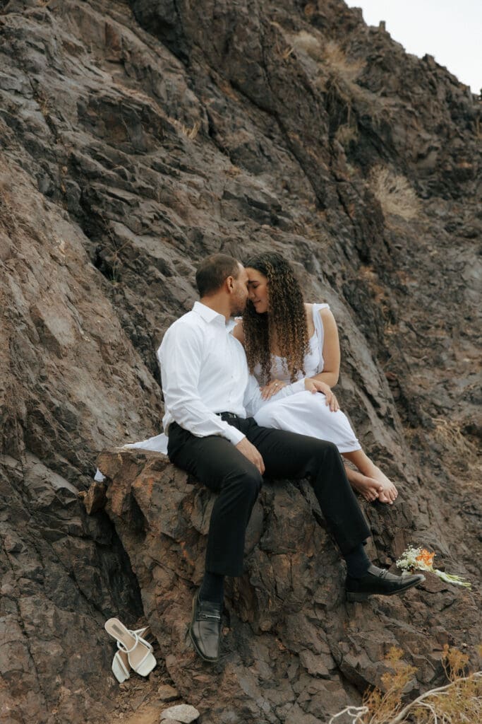 bride and groom sitting on a rock touching foreheads