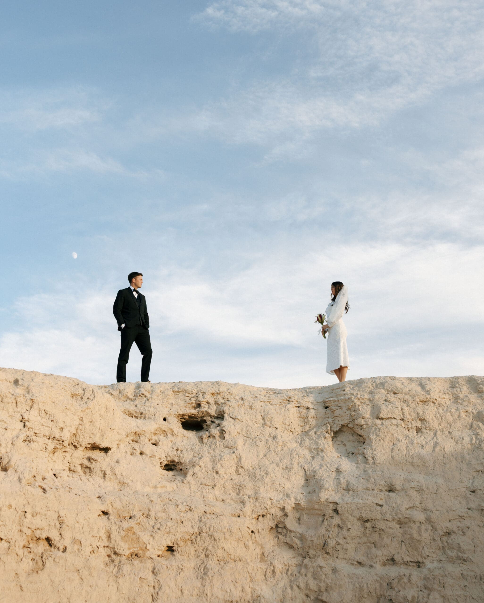couple standing on cliff at outdoor location for engagement photos las vegas