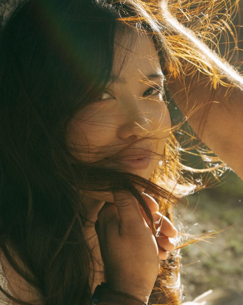 guy holding fiances chin as she is looking at the camera with windswept hair