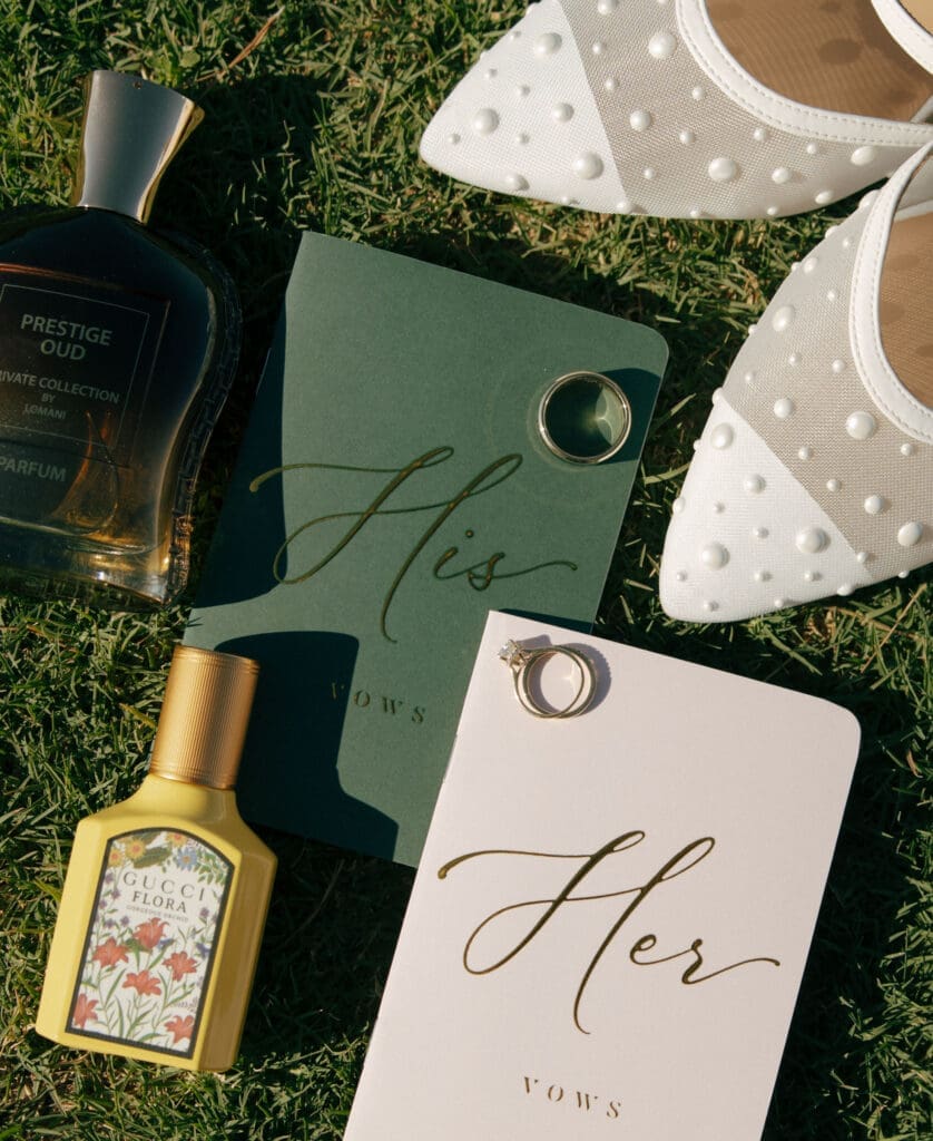flat lay of bride and grooms vow books, rings, and perfume, in las vegas