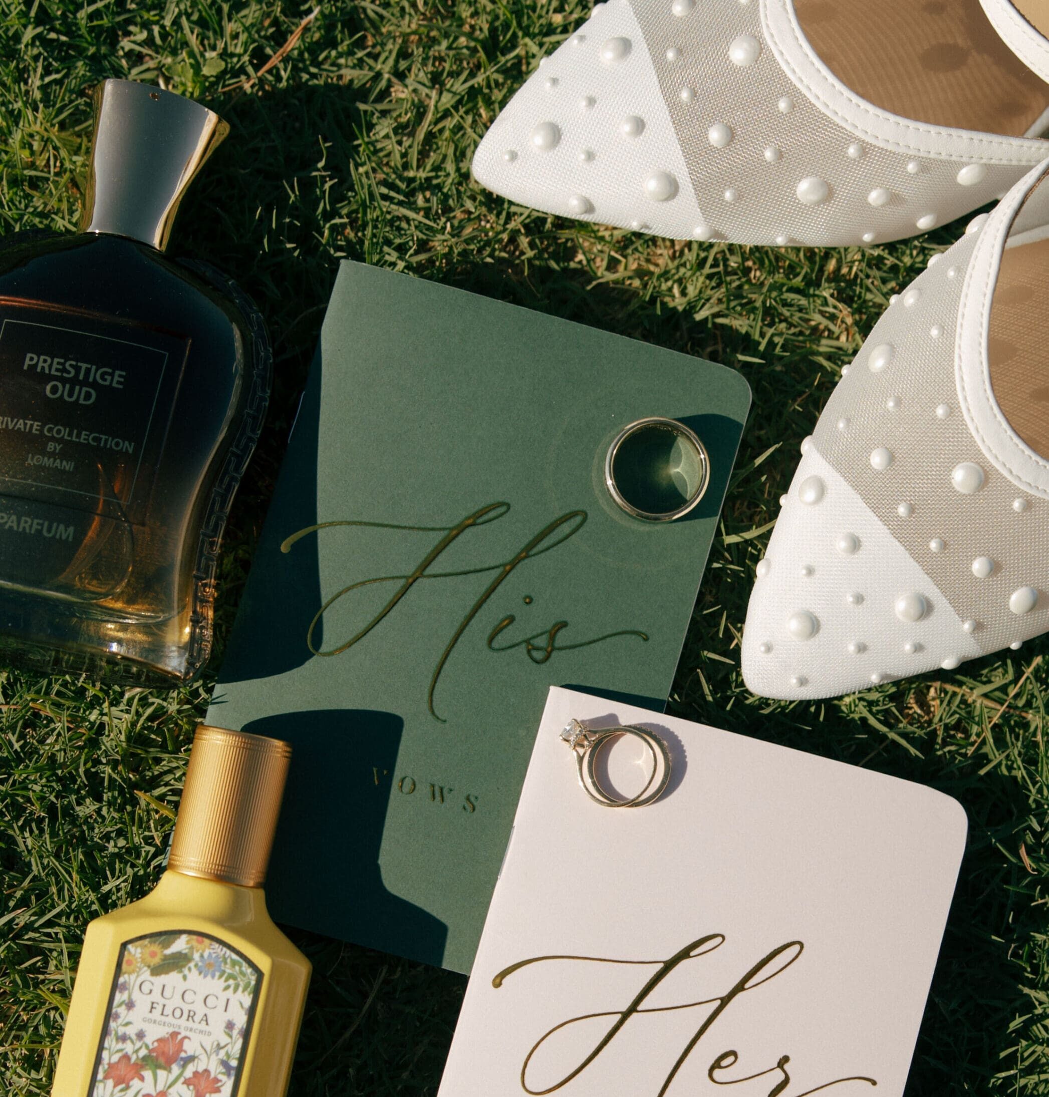 flat lay of bride and grooms vow books, rings, and perfume, in las vegas