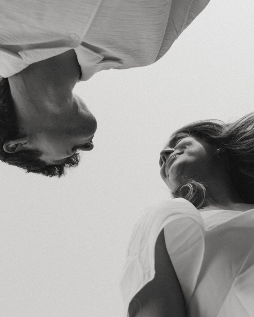low angle of couple looking at each other with the sky creating negative space