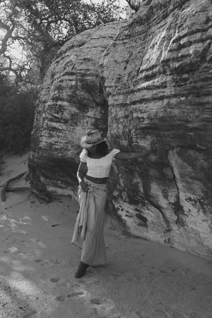 black and white image of woman playing with her skirt in the desert