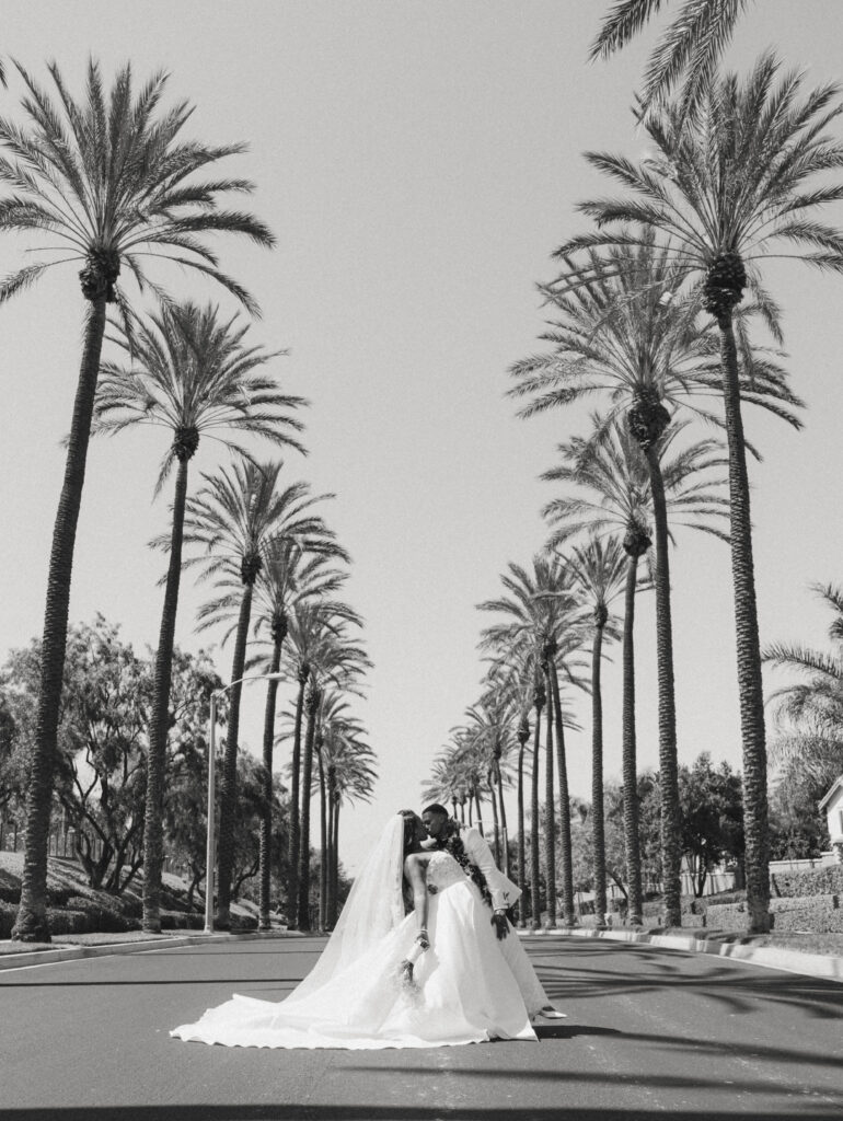 bride and groom kissing between rows of palm trees