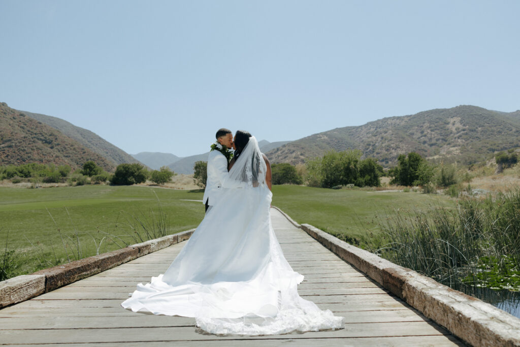 bride and groom kissing on a bridge in southern california