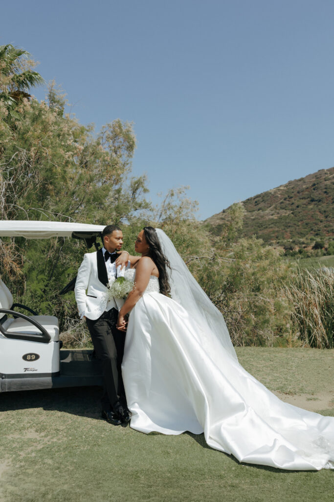 bride and groom leaning on a golf cart
