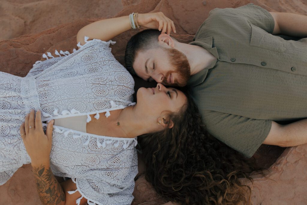 couple laying down on red rocks