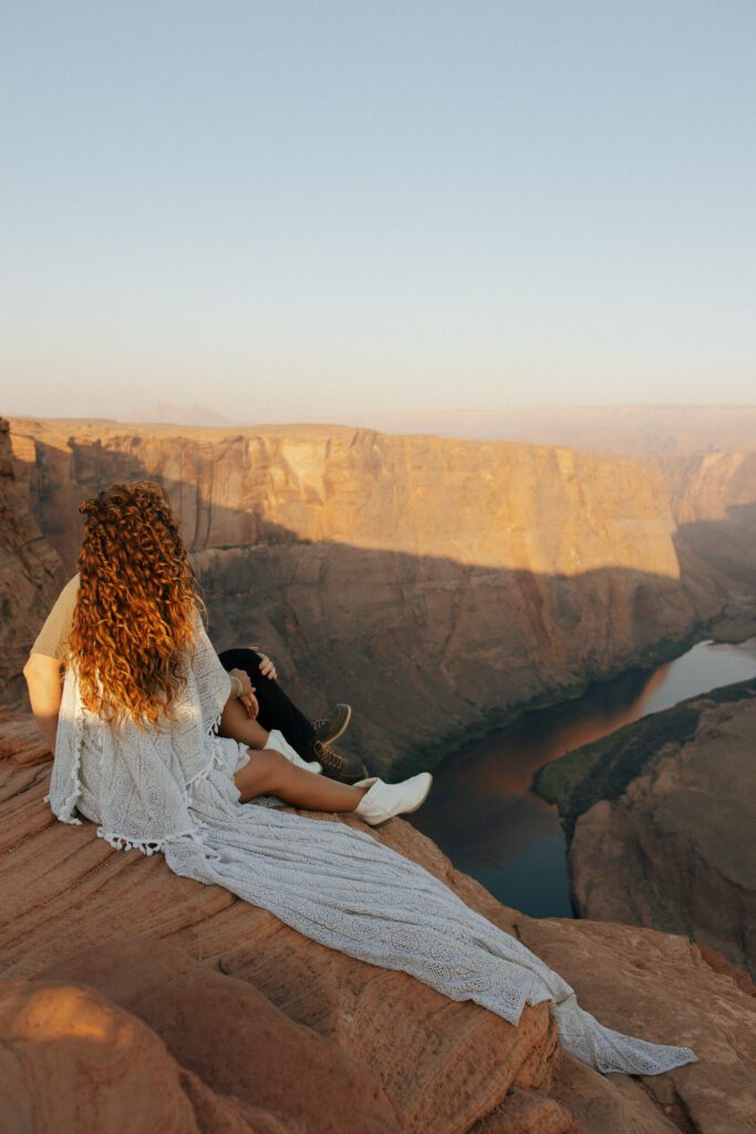 couple sitting on the edge of a cliff in arizona
