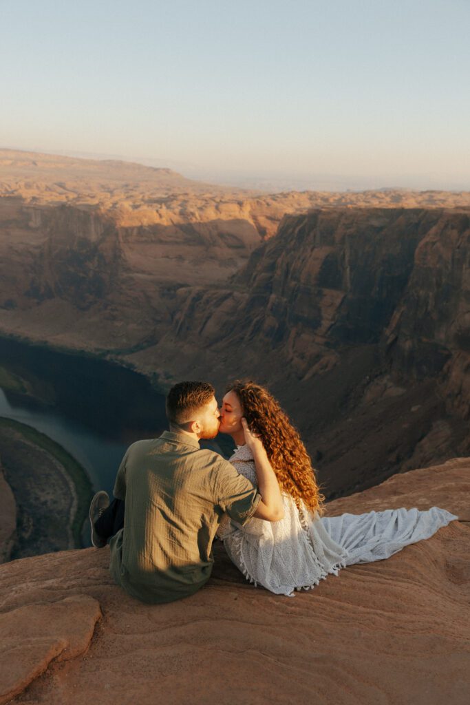 bride and groom sitting on the edge of a cliff for horseshoe bend couples session