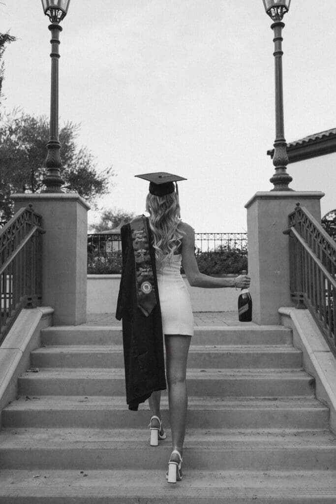 woman in cap and gown holding a bottle of champagne