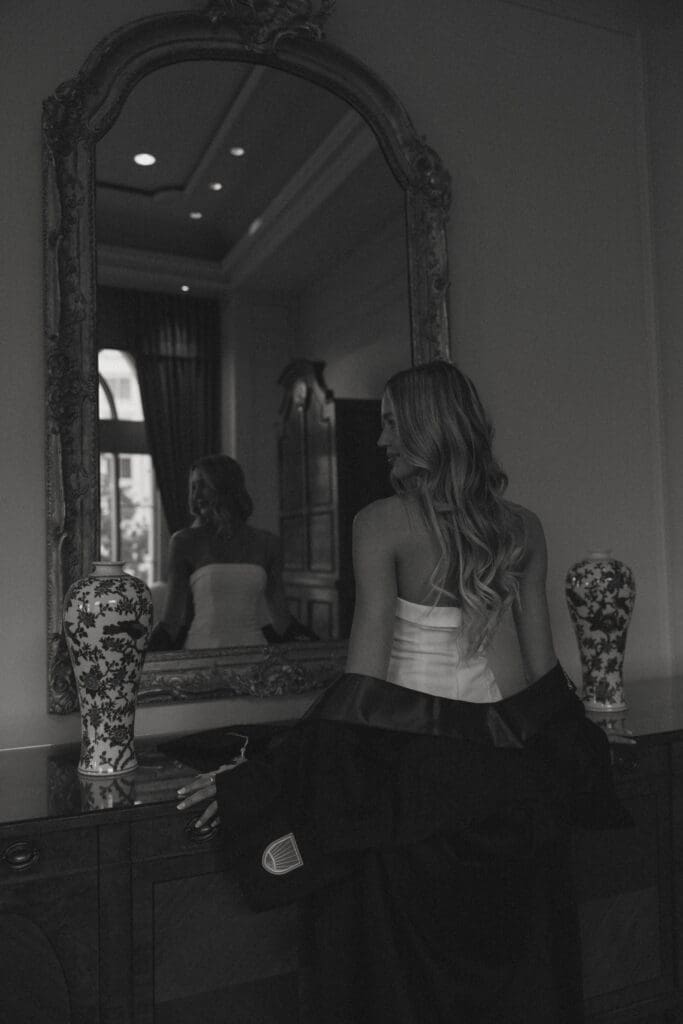 black and white image of a woman in front of a mirror