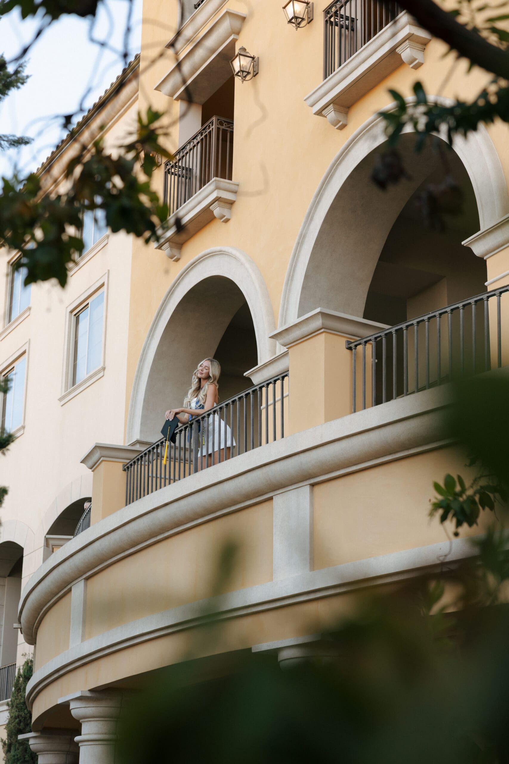 woman holding grad cap over a balcony at lake las vegas