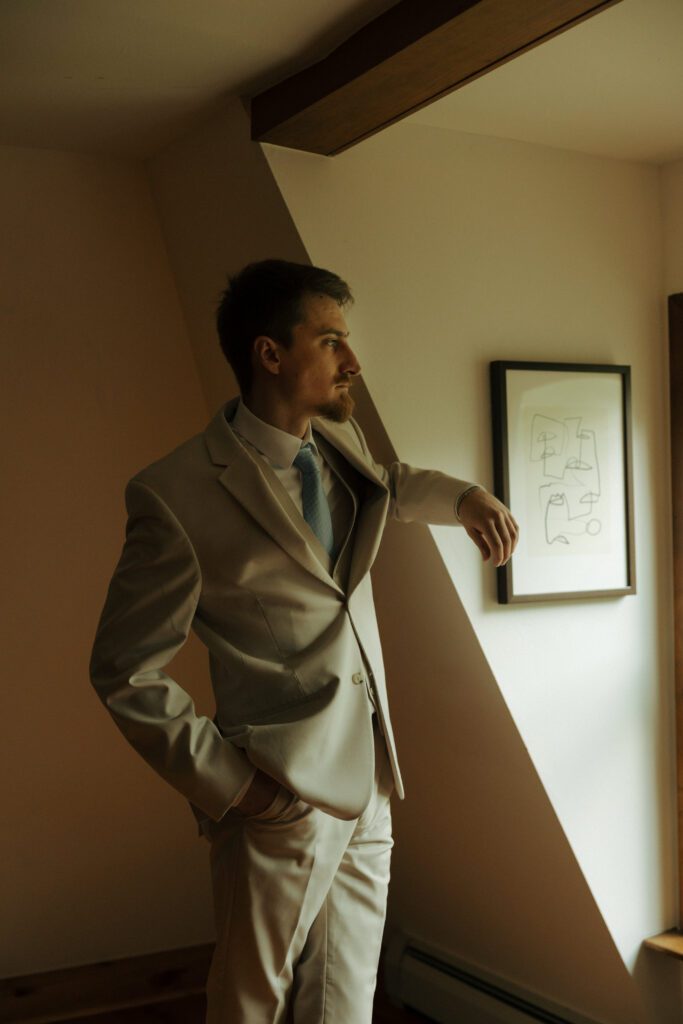 groom looking out a window in vail