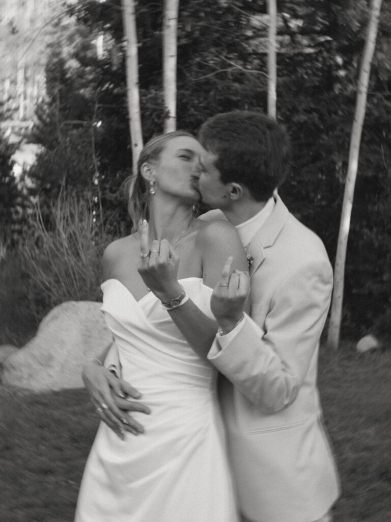 bride and groom kissing holding up ring finger