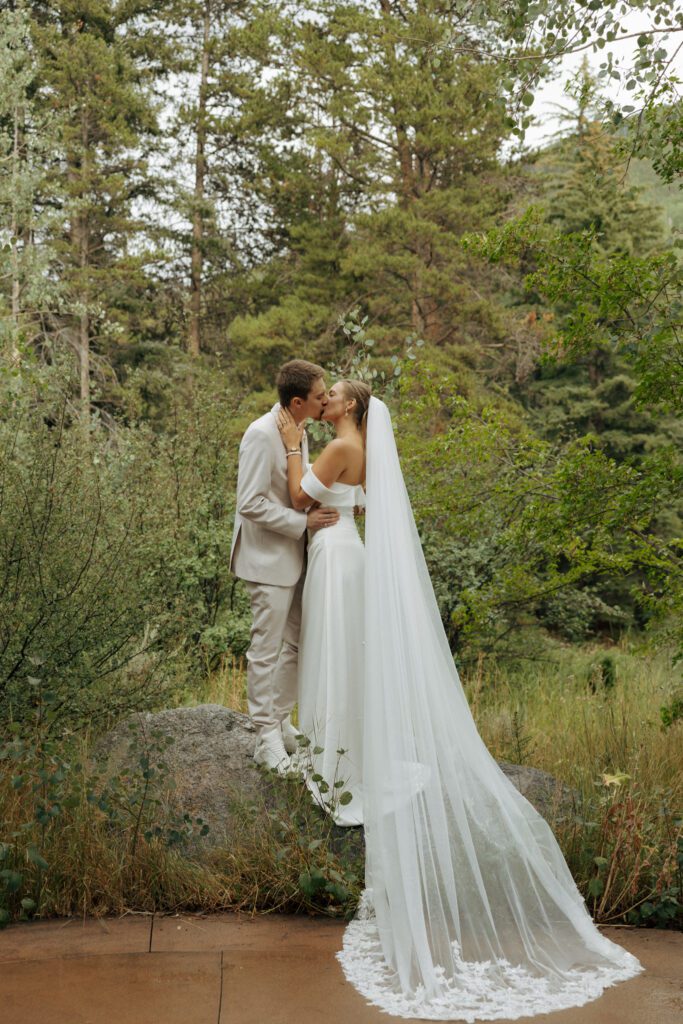 bride and groom kissing on a rock in vail colorado