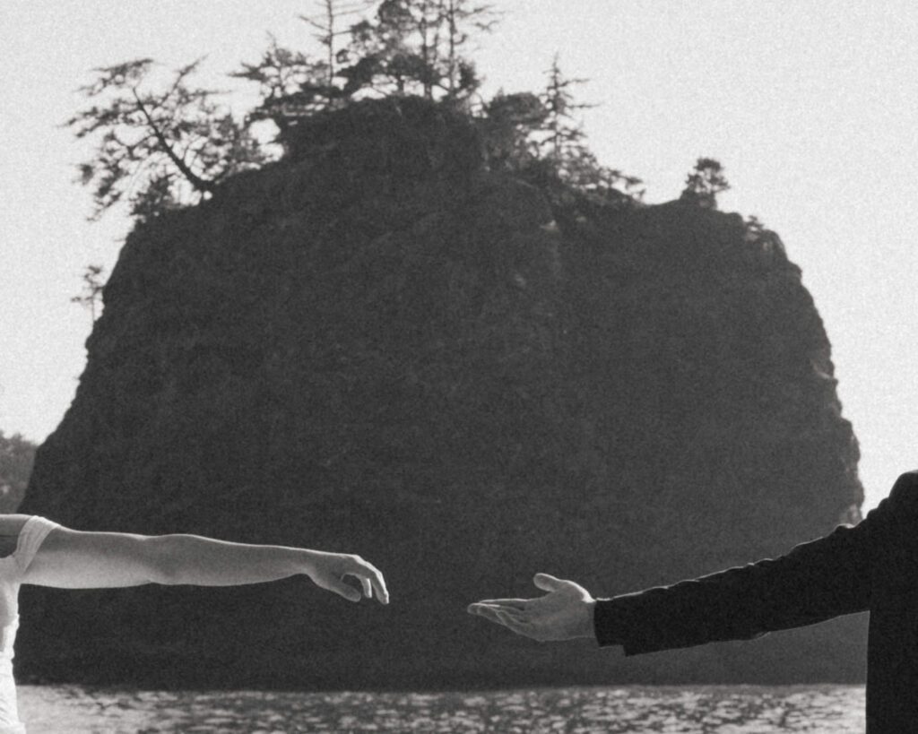 couple reaching for each other on the oregon coast